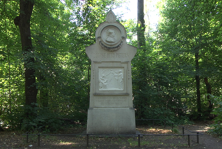 Mittig platziert ist hier ein umzäuntes Denkmal zu erkennen, bei dem im oberen Bereich das Abbild einer älteren Frau herausgearbeitet wurde und der Schriftzug „LOUISE OTTO PETERS“ zu lesen ist. Darunter befindet sich ein herausgearbeitetes Bild und ein weiterer Schriftzug, der aber nicht zu lesen ist.